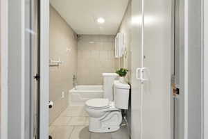 Bathroom with tile walls, toilet, tile patterned floors, and shower / bathtub combination