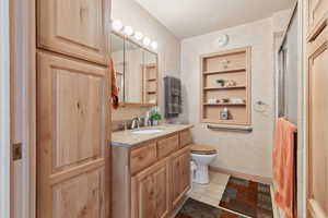 Bathroom featuring vanity, an enclosed shower, toilet, and tile patterned floors