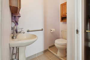 Half bathroom featuring toilet, tile patterned floors, and baseboards