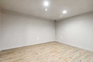 Spare room featuring light wood finished floors, baseboards, recessed lighting, and ornamental molding