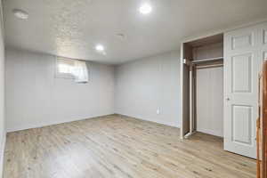 Unfurnished bedroom featuring light wood-style flooring, a closet, and baseboards