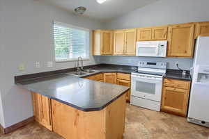 Kitchen featuring white appliances, a sink, light brown cabinets, and lofted ceiling