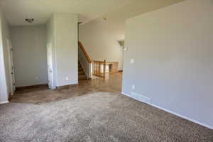 Carpeted spare room with baseboards and stairs