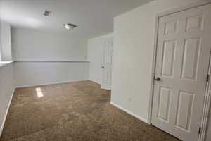 Spare room featuring carpet flooring and baseboards