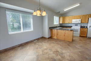 Kitchen featuring white appliances, a sink, baseboards, dark countertops, and a chandelier