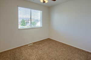 Spare room with a ceiling fan, carpet flooring, and baseboards