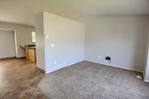 Carpeted empty room with baseboards and lofted ceiling