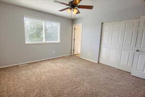 Unfurnished bedroom with carpet, a closet, baseboards, and ceiling fan