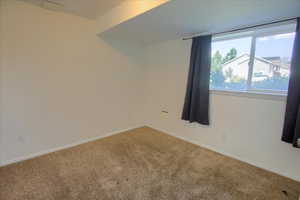 Spare room featuring carpet and baseboards