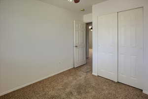 Unfurnished bedroom featuring carpet floors, baseboards, and a closet