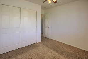 Unfurnished bedroom with light carpet, a closet, baseboards, and ceiling fan