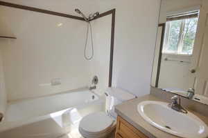 Bathroom featuring toilet, vanity, and shower / washtub combination