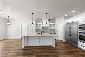Kitchen with built in refrigerator, a textured ceiling, baseboards, recessed lighting, and tasteful backsplash