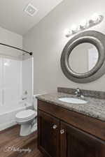 Bathroom with vanity, wood finished floors, tub / shower combination, and toilet