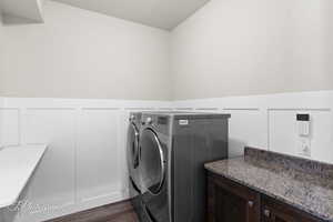Laundry room with independent washer and dryer, dark wood finished floors, wainscoting, and a decorative wall