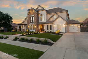 View of front of home featuring board and batten siding, stone siding, concrete driveway, and stucco siding