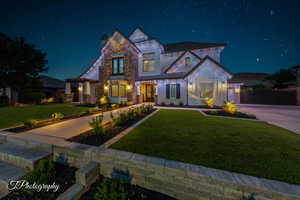 View of front of home featuring a lawn and custom lighting options