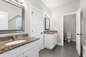 Bathroom featuring two vanities, toilet, and baseboards