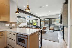 Kitchen featuring open floor plan, light wood-style flooring, modern cabinets, light brown cabinets, and light countertops