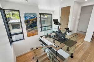 Exercise area with light wood-style flooring, baseboards, and recessed lighting
