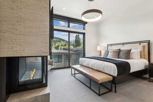 Primary bedroom with access to exterior, a high ceiling, a multi sided fireplace, and a mountain view