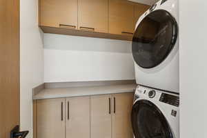 Washroom with cabinet space and estacked washer and dryer