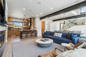 Living room with stairway, light wood-type flooring, a glass covered fireplace, wet bar, and recessed lighting