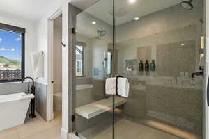 Primary Full bathroom featuring tile walls, toilet, a freestanding tub, a shower stall, and tile patterned floors