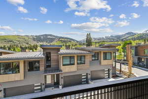 Primary Bedroom View of front facade featuring a standing seam roof, a mountain view, an attached garage, and metal roof