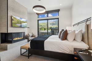 Primary bedroom featuring access to exterior, a fireplace, and recessed lighting