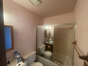 Full bathroom with toilet, enclosed tub / shower combo, and vanity