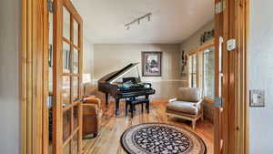 Living area featuring light wood-style flooring, rail lighting, french doors, and a wainscoted wall
