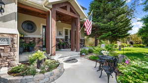 View of exterior entry featuring a porch, stone siding, and stucco siding