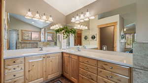 Full bathroom with lofted ceiling, double vanity, and healthy amount of natural light