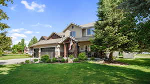 Craftsman inspired home featuring stucco siding, a garage, a front lawn, and stone siding