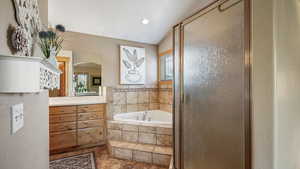Bathroom with vanity, healthy amount of natural light, a bath, and a shower stall