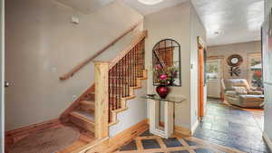 Staircase featuring baseboards and stone tile floors