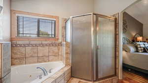 Bathroom featuring ensuite bath, a shower stall, and a tub with jets