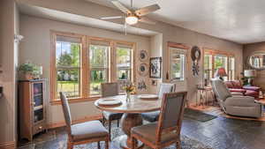 Dining room with stone tile flooring, healthy amount of natural light, ceiling fan, and baseboards