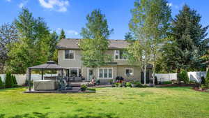 Back of property featuring a hot tub, a gazebo, stucco siding, and a patio area