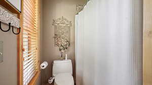 Bathroom with toilet and curtained shower