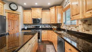 Kitchen with appliances with stainless steel finishes, a sink, light brown cabinetry, recessed lighting, and decorative backsplash