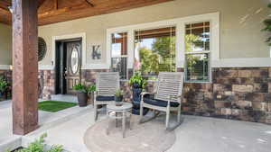 Entrance to property with a porch, stone siding, and stucco siding