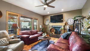 Living area with wood finished floors, ceiling fan, a fireplace, and recessed lighting