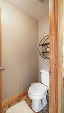 Bathroom with toilet, a textured ceiling, and baseboards