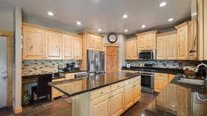 Kitchen featuring appliances with stainless steel finishes, a sink, light brown cabinets, a kitchen island, and recessed lighting