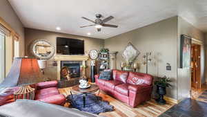 Living room featuring ceiling fan, baseboards, a tile fireplace, recessed lighting, and stone finish flooring