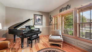 Living area featuring light wood-style flooring, a decorative wall, and wainscoting