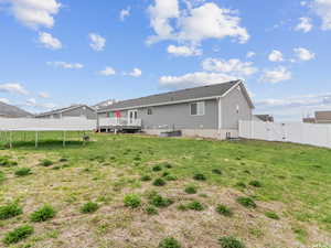 Rear view of house with a gate, a trampoline, a deck, and central AC