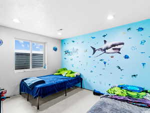 Bedroom with recessed lighting, wallpapered walls, and concrete flooring